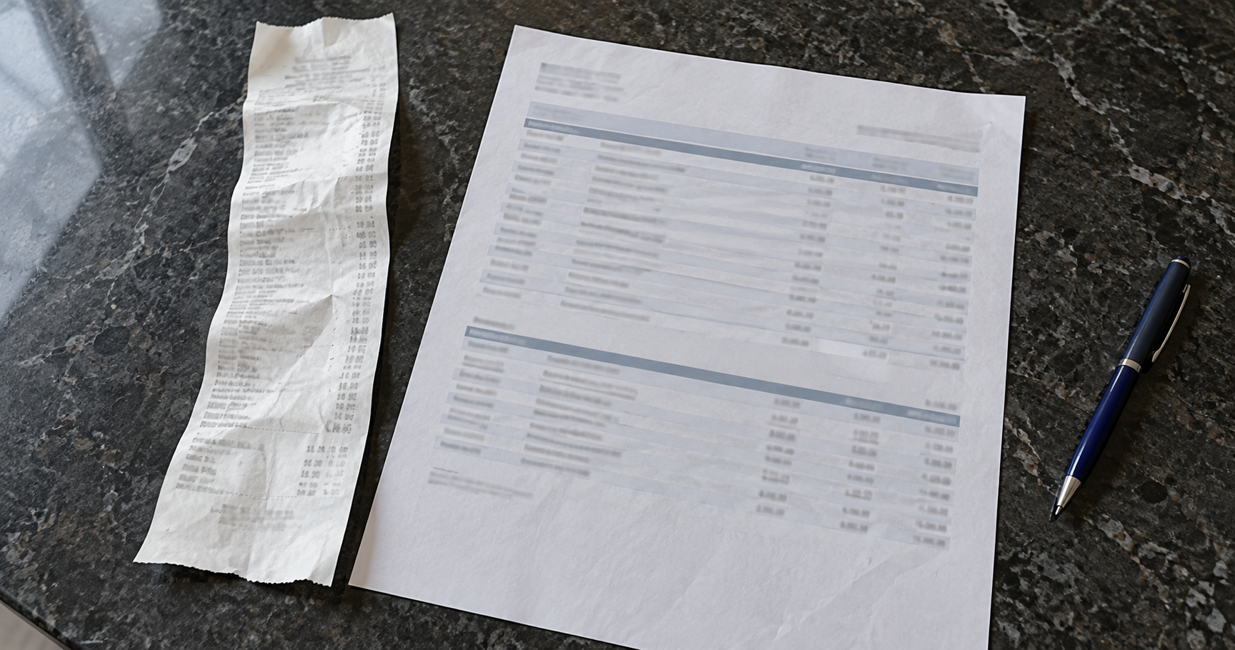 A thermal receipt beside a printed bank statement and a blue pen.